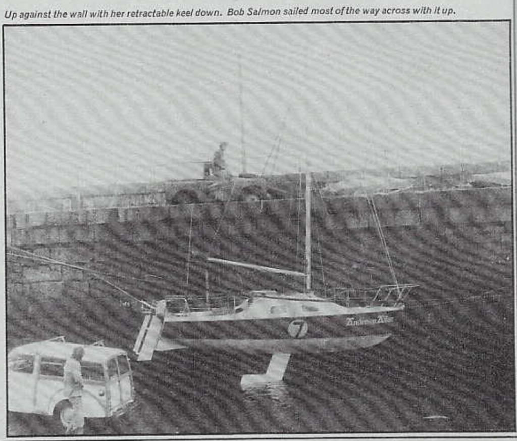 The Anderson Affair, suspended over the water. The boat is shown with its retractable keel in the down position, with a caption noting that the author, Bob Salmon, "sailed most of the way across with it up